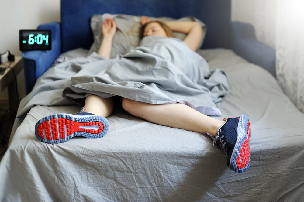 en tjej som ligger och sover i en säng med träningsskorna på för att bränna fett och gå ner i vikt i sömnen
